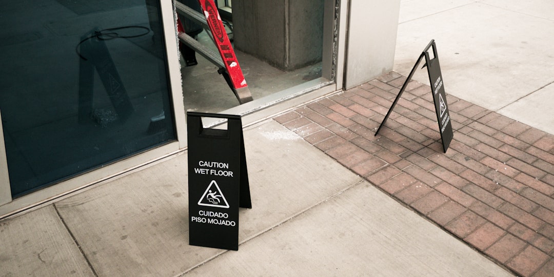caution-wet-floor-sign-on-paved-walkway-outside-building-entrance-lzkrawf6pfc